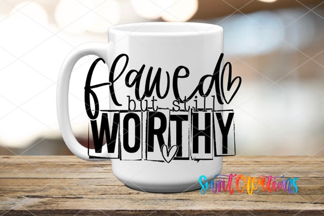a white coffee mug with a black lettering that says, flawed but still