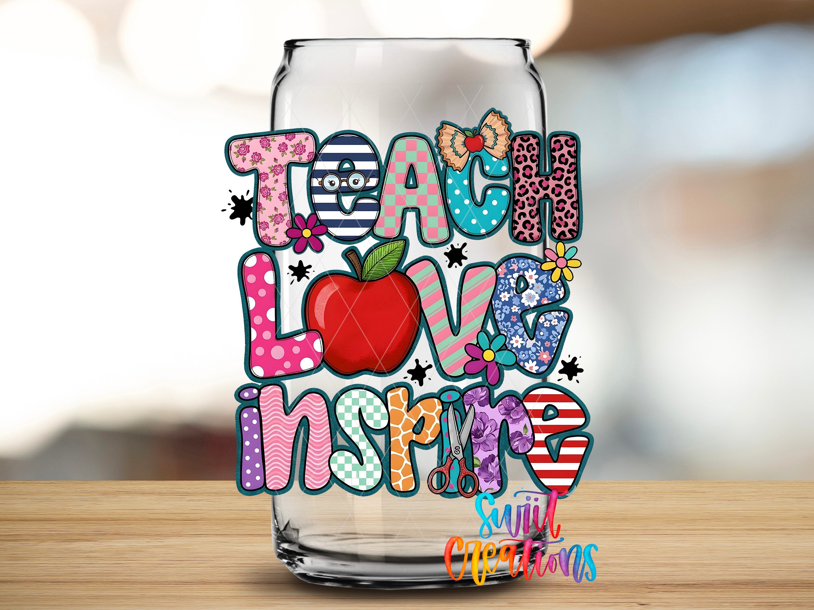 A glass jar with colorful text and illustrations, including the words "Teach Love Inspires" and an apple, on a wooden surface.