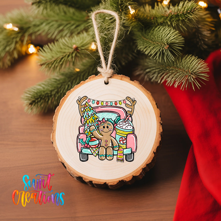 A wooden ornament featuring a gingerbread man sitting in a truck, surrounded by Christmas decorations, is hanging on a Christmas tree.