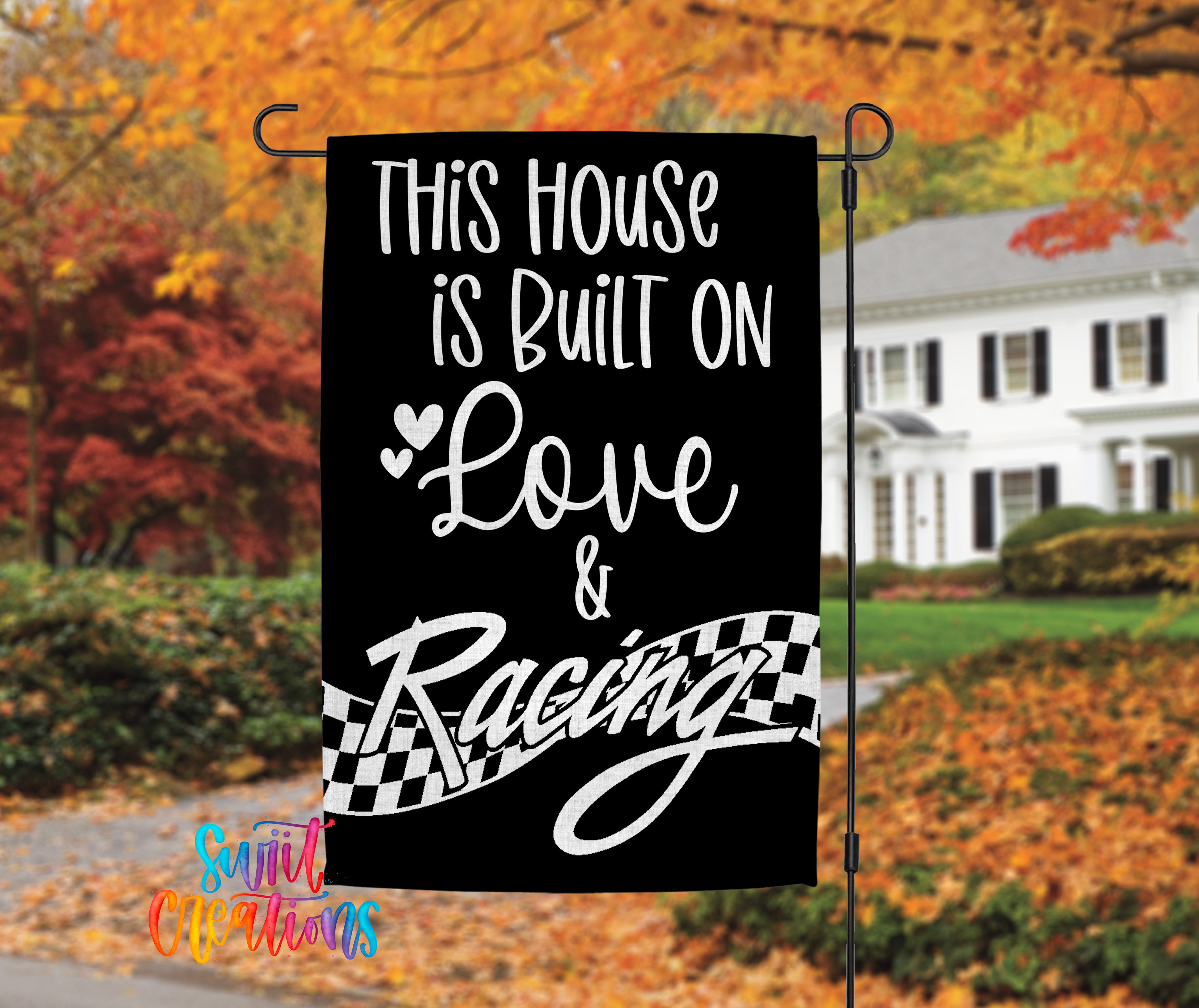 a black and white banner with white text that reads "This house is built on love & racing", set against a backdrop of autumn foliage.