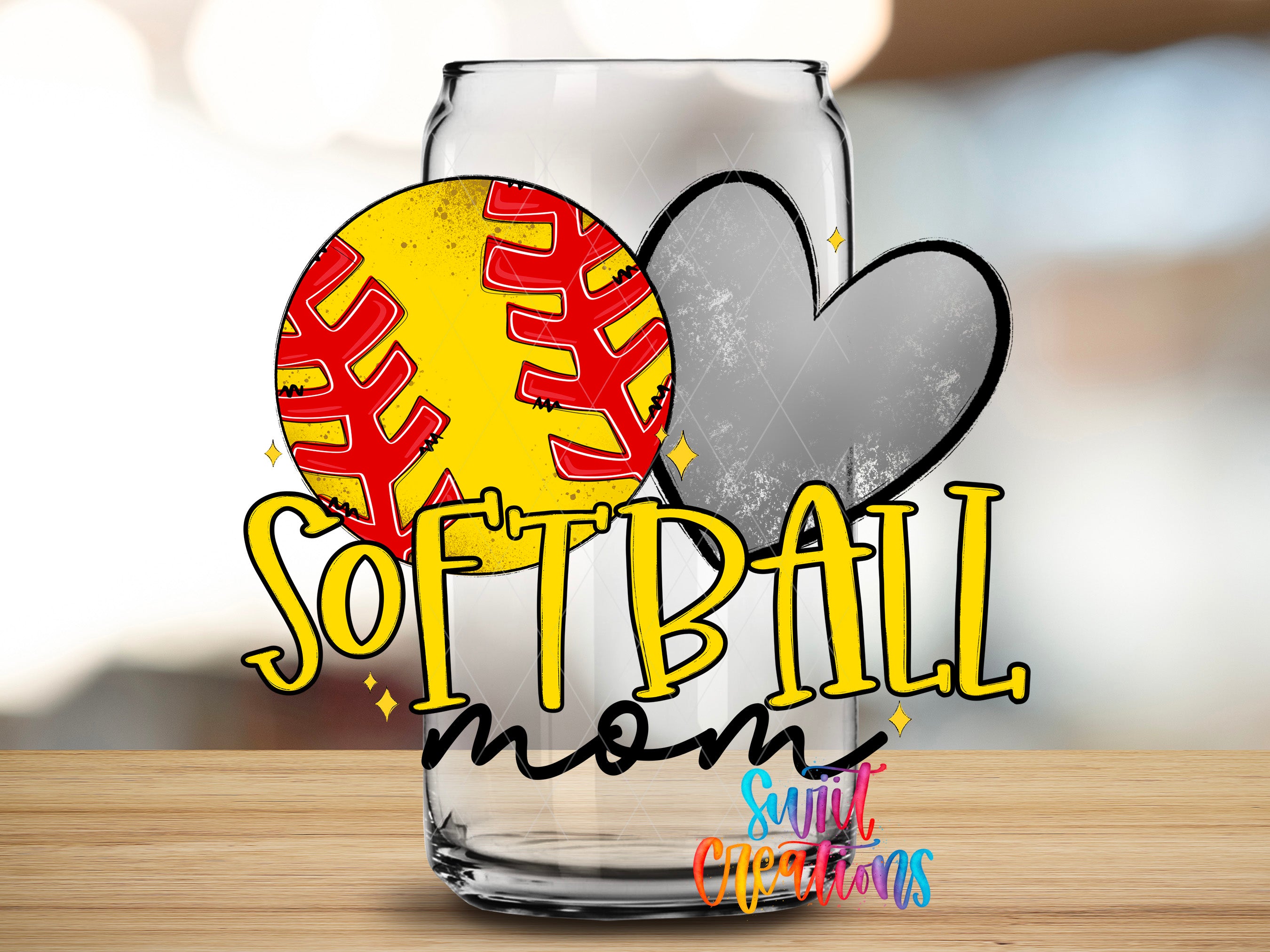 A glass mug with a yellow and red softball design, along with a heart and the text "SOFTBALL mom" written on it.
