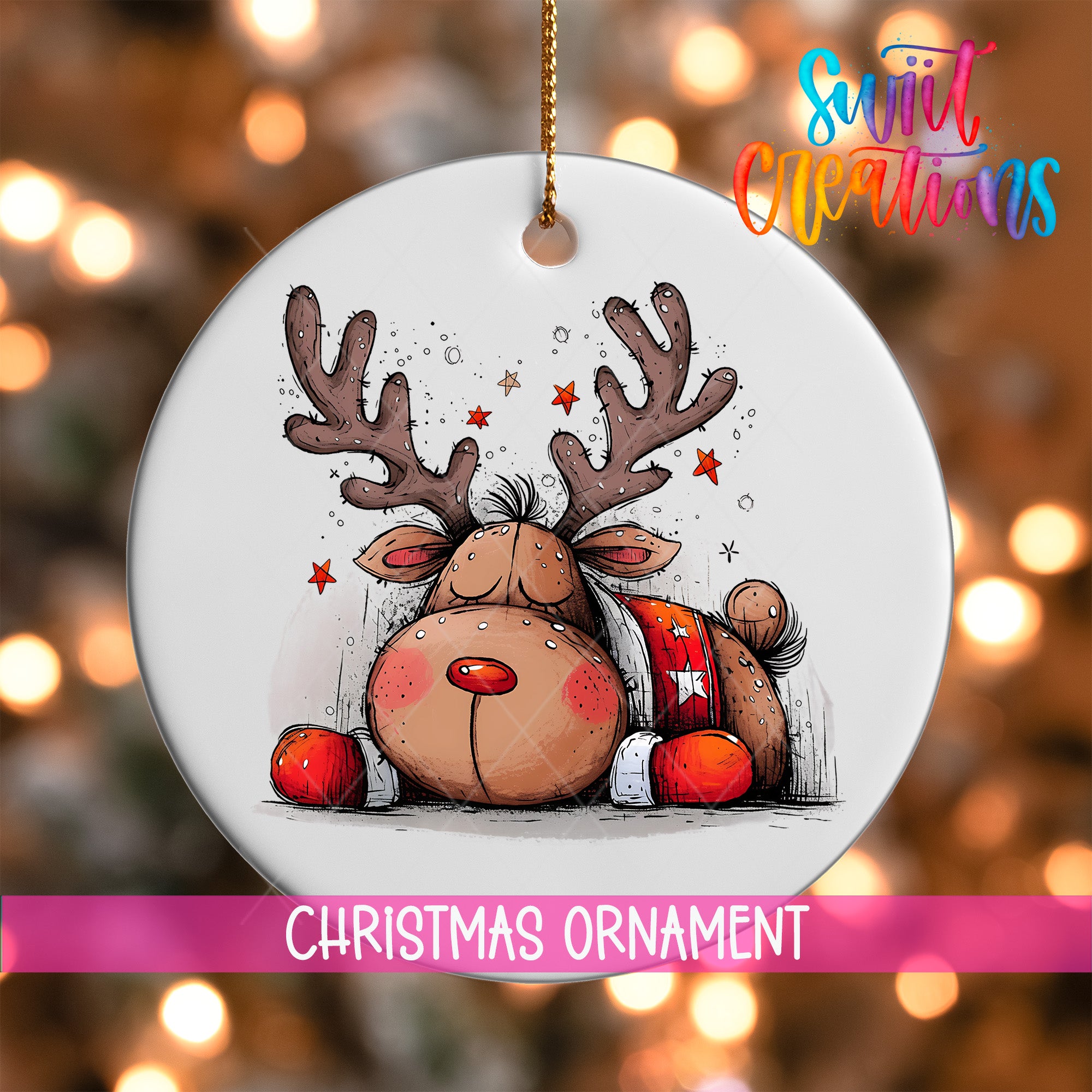 A white Christmas ornament featuring a cartoon reindeer with antlers and a red bow tie, surrounded by stars, against a blurred background with Christmas lights.