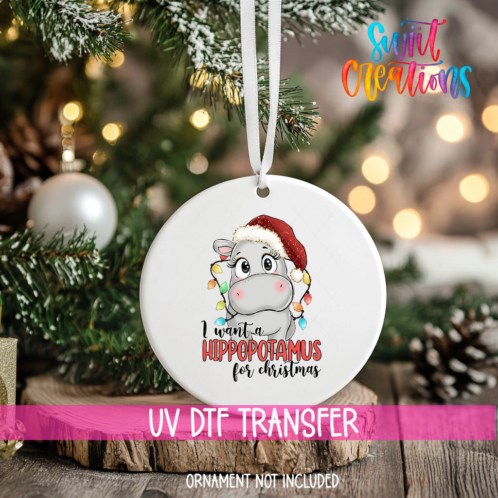 A white ornament with a cartoon image of a hippopotamus wearing a Santa hat, along with the text "I want a hippopotamus for Christmas".