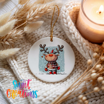 A white ceramic ornament featuring a cartoon reindeer with antlers, surrounded by a cozy, textured background with dried flowers and a lit candle.