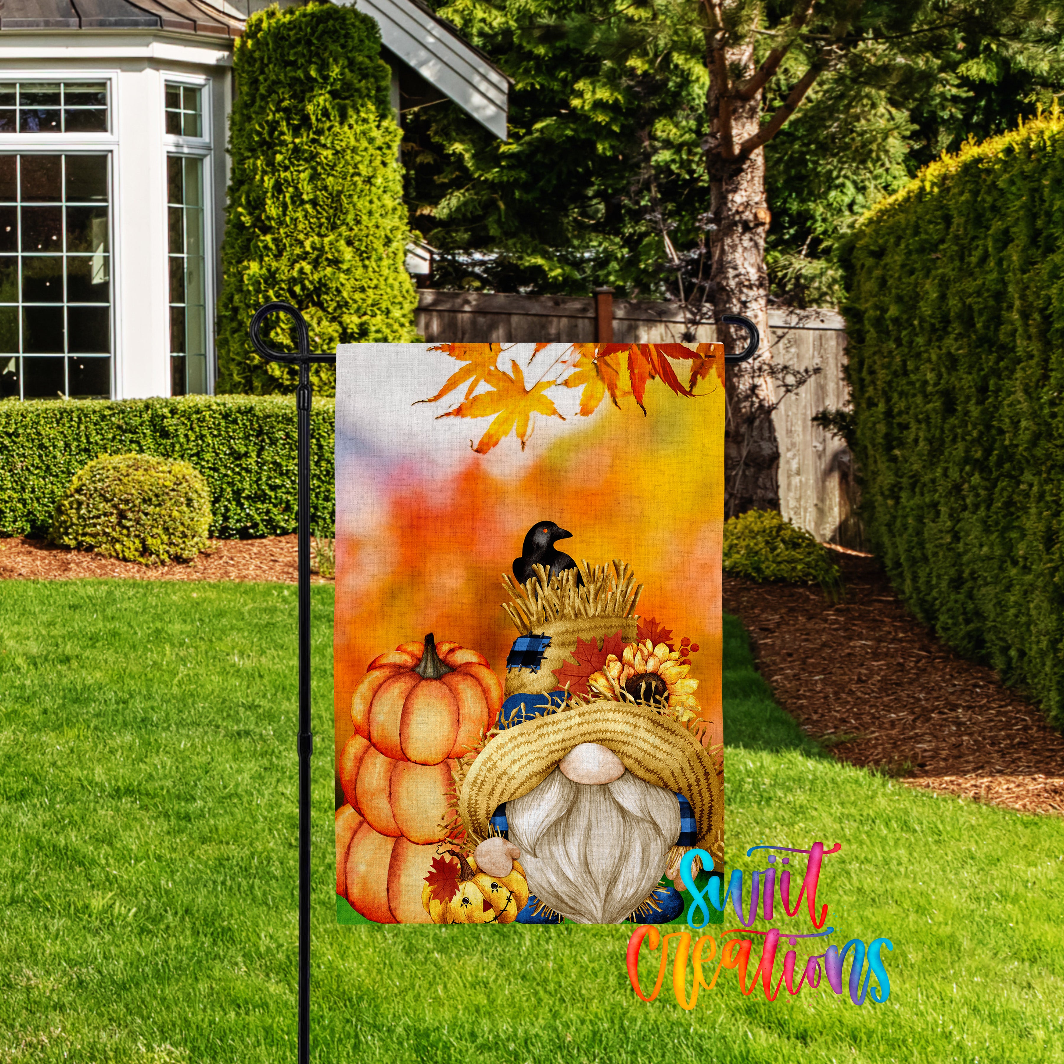 A colorful garden gnome sign with autumn-themed decorations, including pumpkins, a bird, and a straw hat, is displayed in a yard with a house and trees in the background.