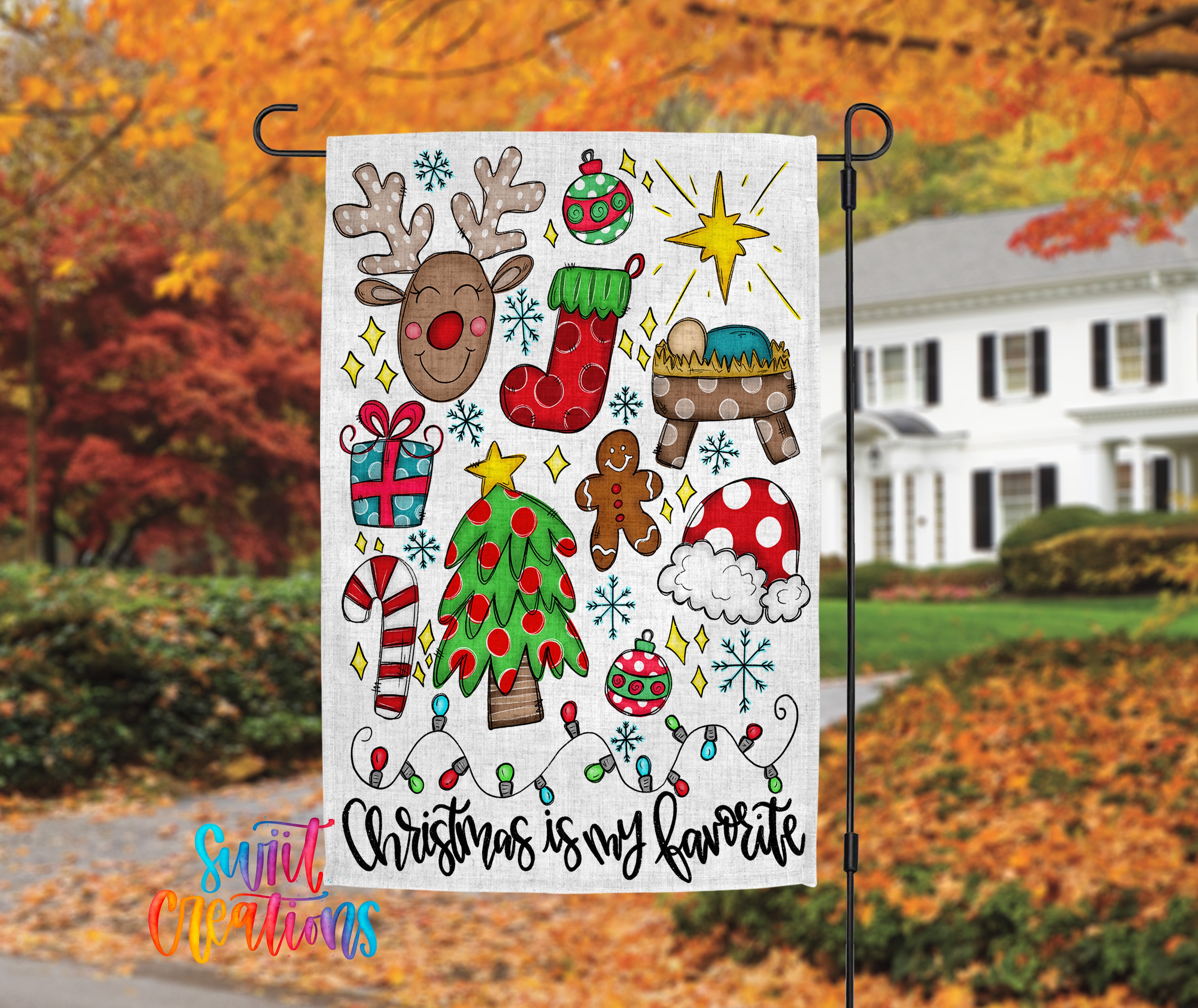 A colorful Christmas-themed flag is displayed in front of a house with autumn foliage in the background.