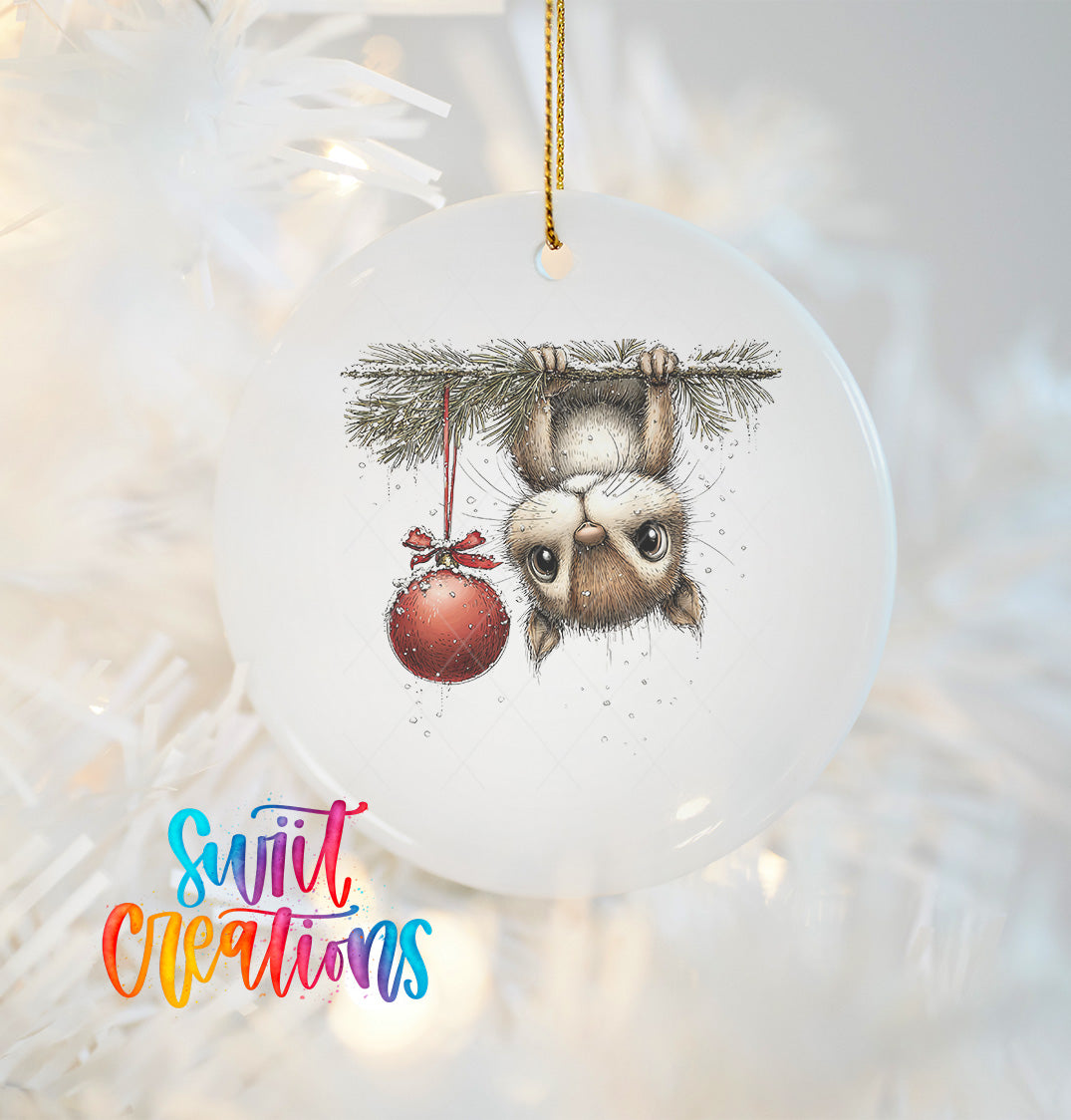 A ceramic ornament featuring a cute cartoon illustration of a cat hanging from a tree branch with a red ornament.
