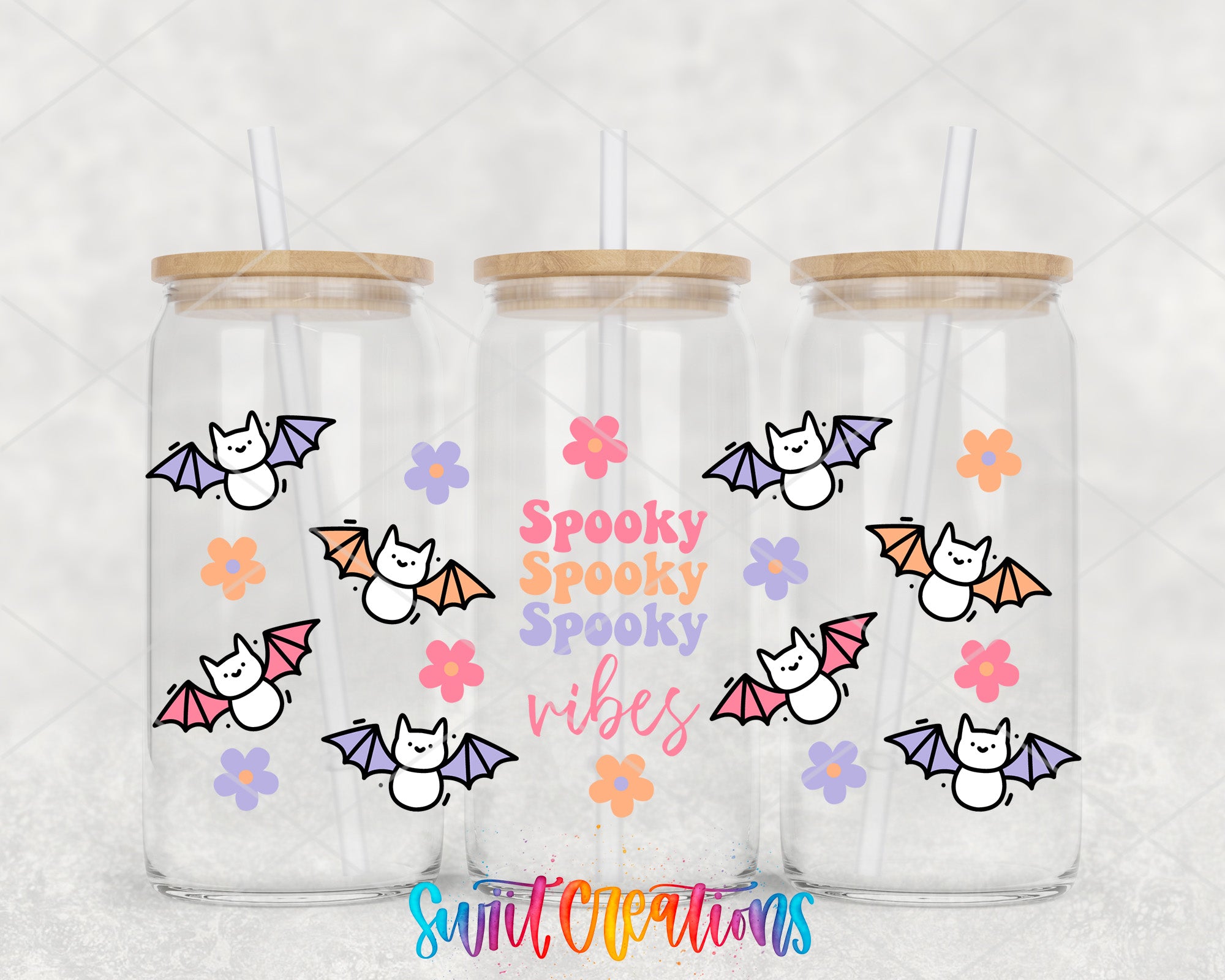 three clear glass tumblers with wooden lids, each adorned with a playful design of bats and flowers. The text "Spooky Spooky Vibes" is written in a colorful, whimsical font on the front of each tumbler, adding a festive touch to the overall design.