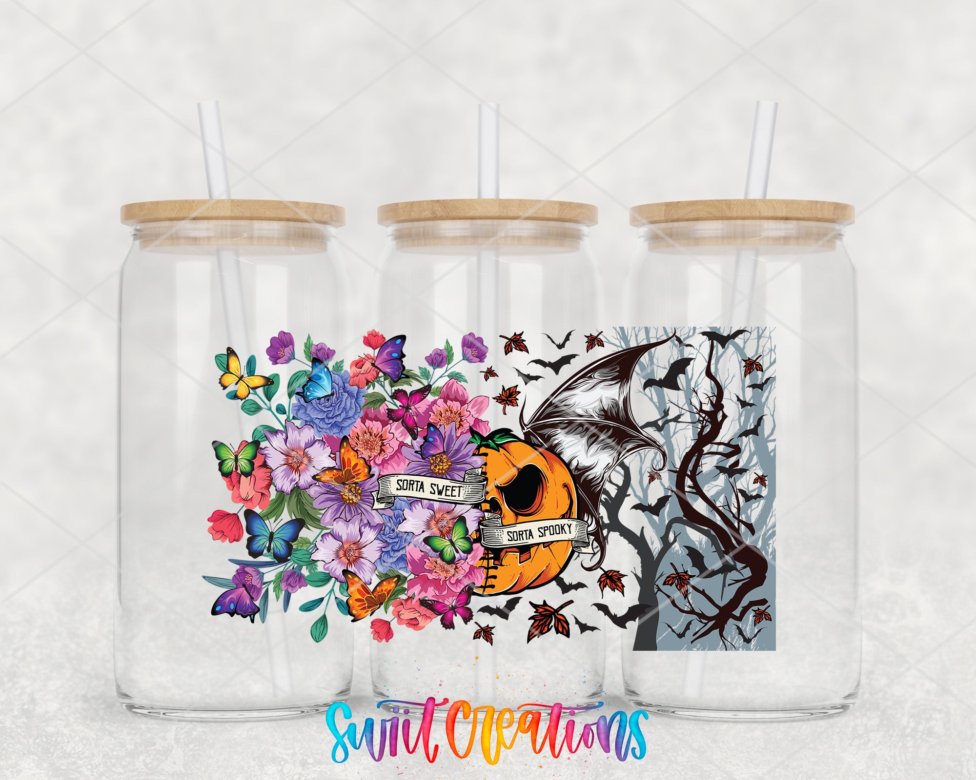 three glass jars with straws, each containing a different design. The jars have a floral and a spooky motif, with a pumpkin and bats as part of the design.