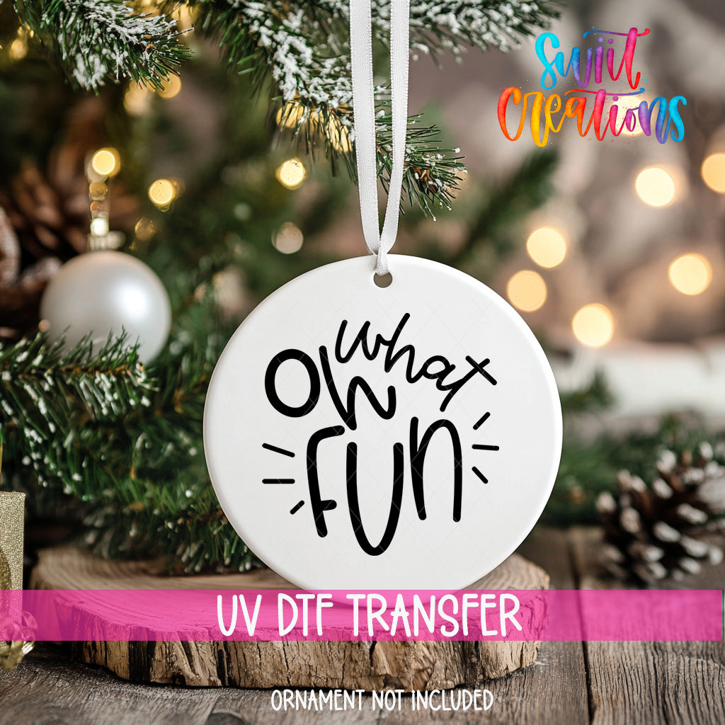A white ornament with the text "oh what fun" hanging from a Christmas tree.