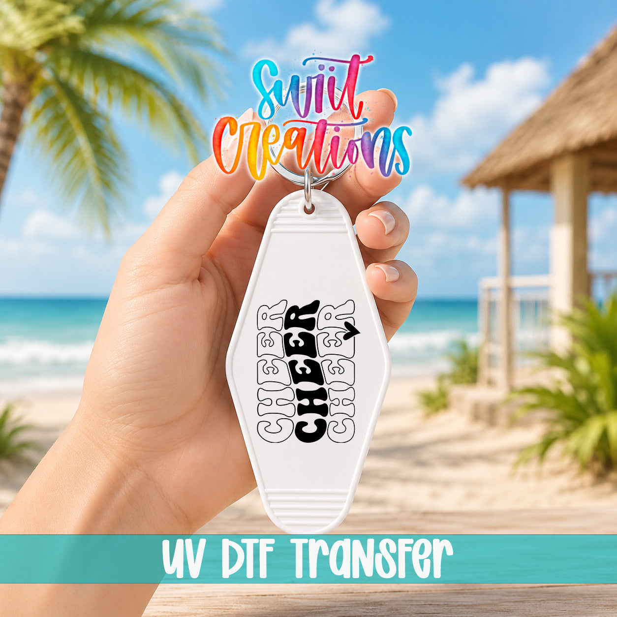 A hand holding a keychain with a design featuring the word "CHEER" in a stylized font, with a tropical beach and palm trees in the background.