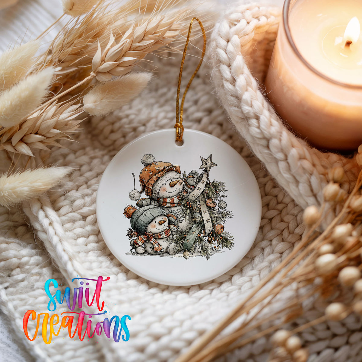 A white ceramic ornament featuring a snowman and other winter-themed elements, hanging on a white knit blanket.