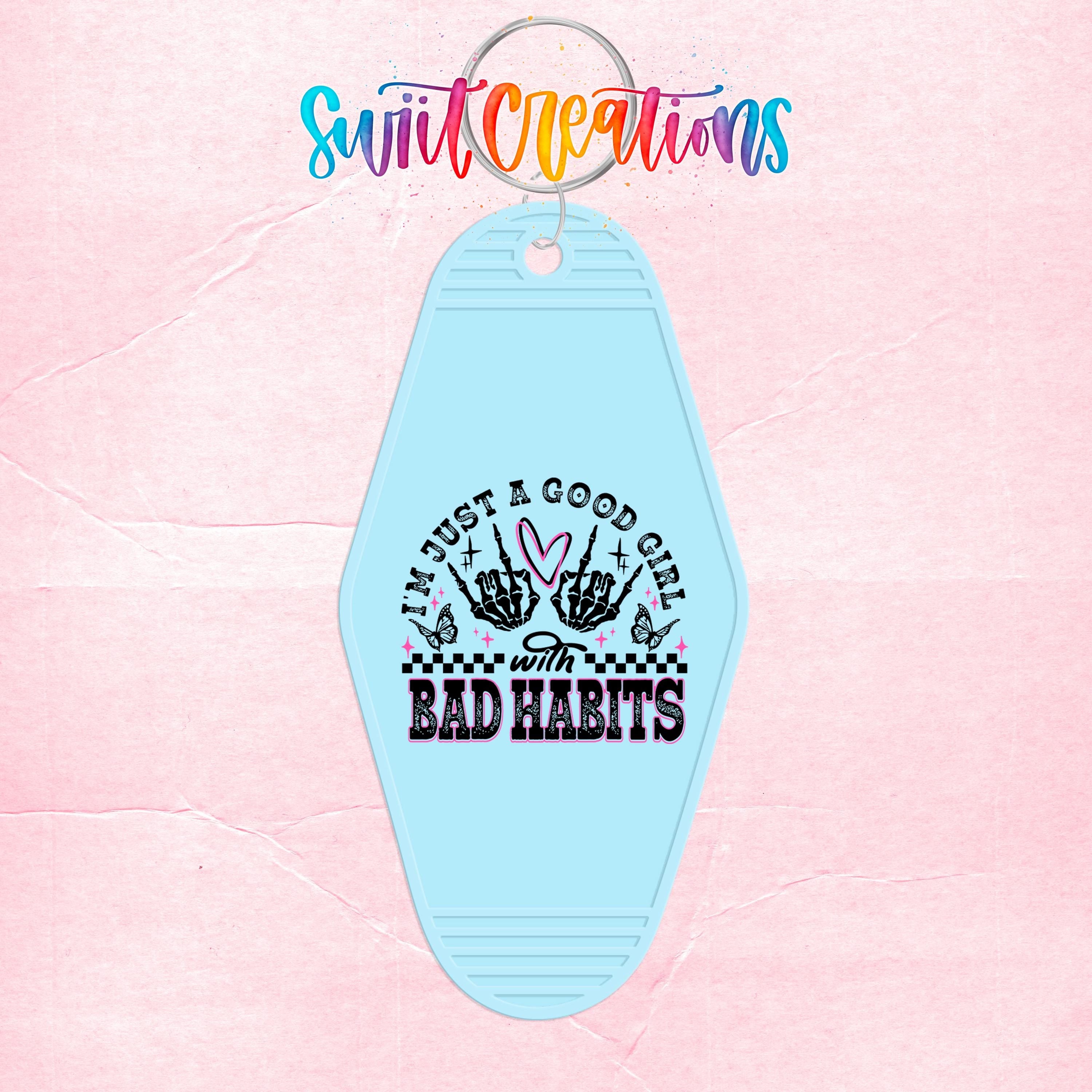 A keychain with a light blue color and a graphic design featuring text and a skeleton hand.