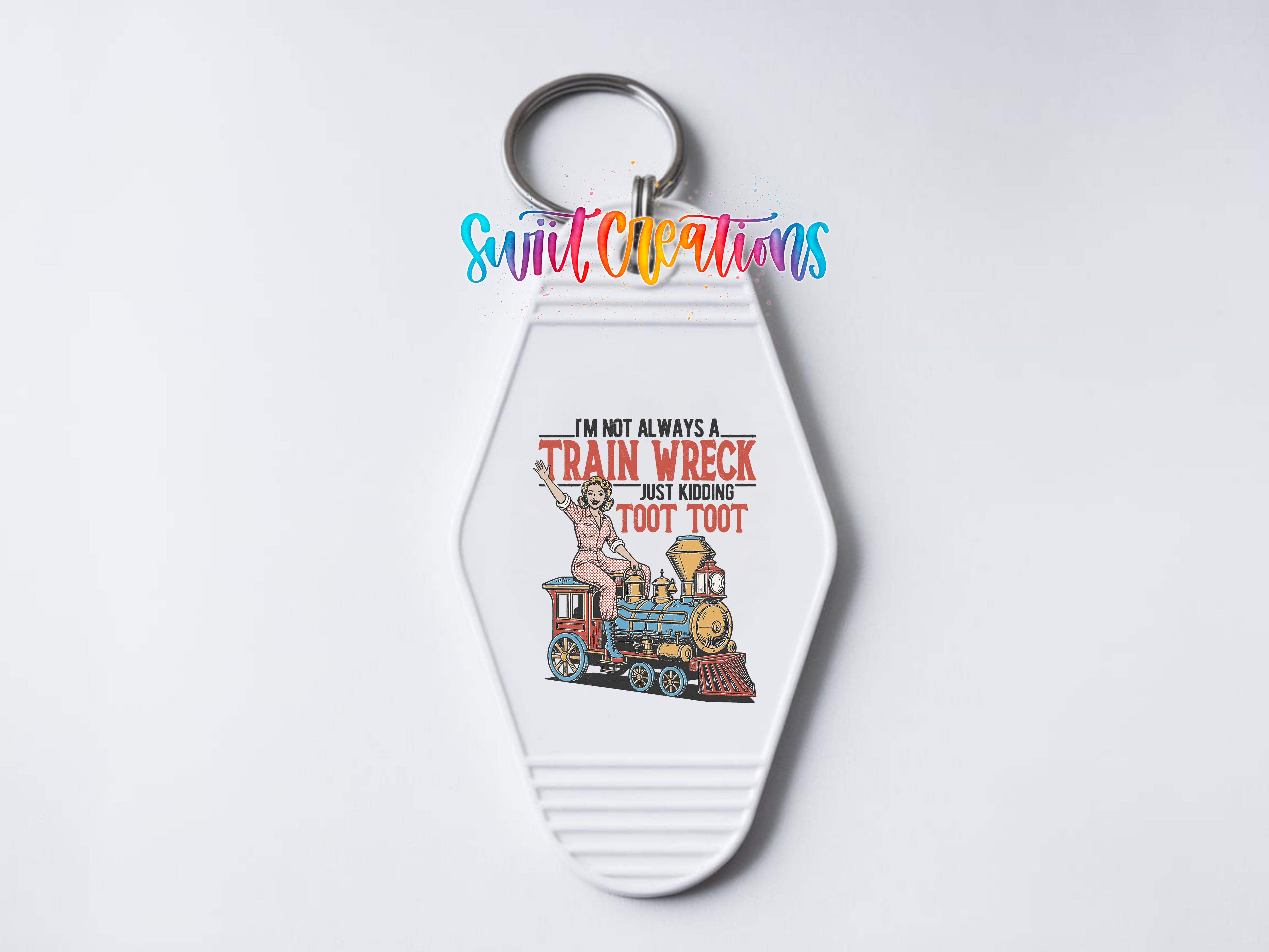 A keychain with a cartoon image of a train and a woman on it, along with text that says "I'm not always a train wreck, but sometimes I'm too much to handle".