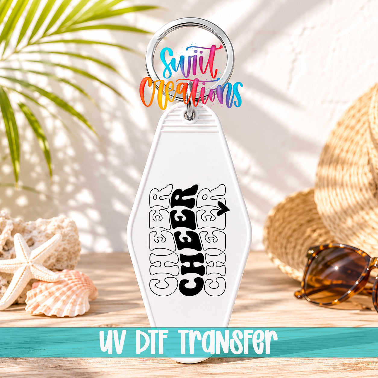 A keychain with the word "CHEER" printed on it, along with a colorful ring and sunglasses on a wooden surface.