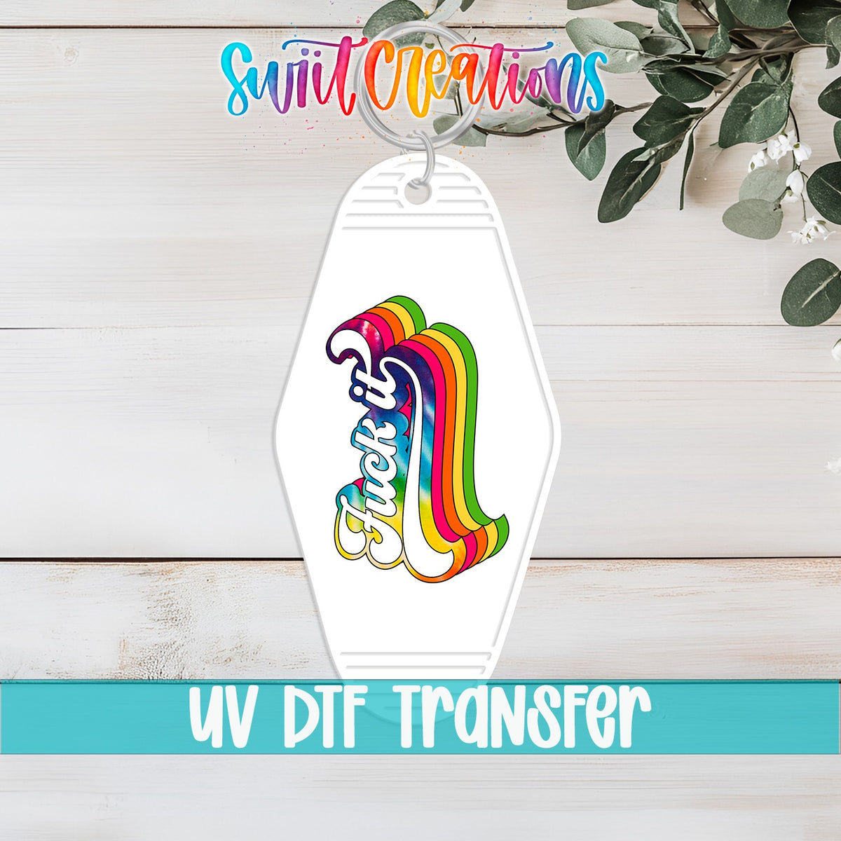 F*ck It UV DTF transfer on a white motel keychain on a white wood table
