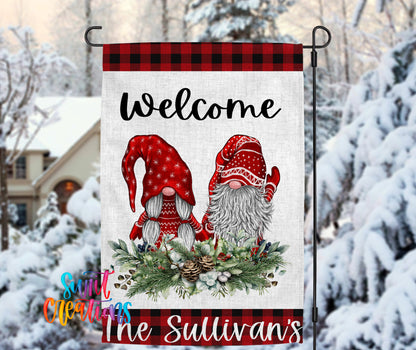 A banner with a welcoming message featuring two gnomes wearing red and white hats, surrounded by a wreath of pine cones and berries, with a snowy background.