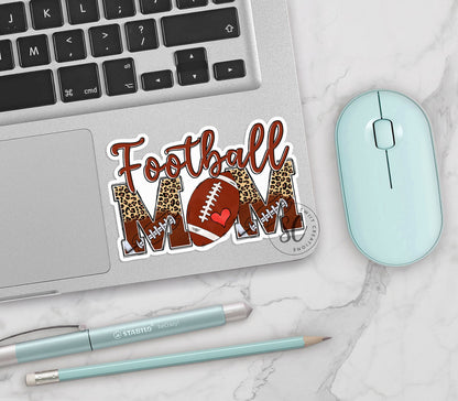 Football Mom vinyl sticker on a silver laptop next to a mint mouse and pens