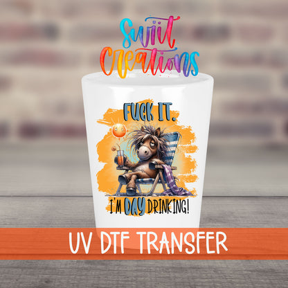 F*ck It I'm Day Drinking UV DTF transfer on a white shot glass in front of a brick wall