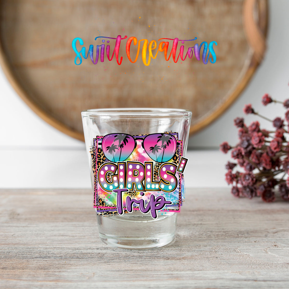 Girls Trip shot glass transfer on a clear glass beside a wooden barrel and dried flowers