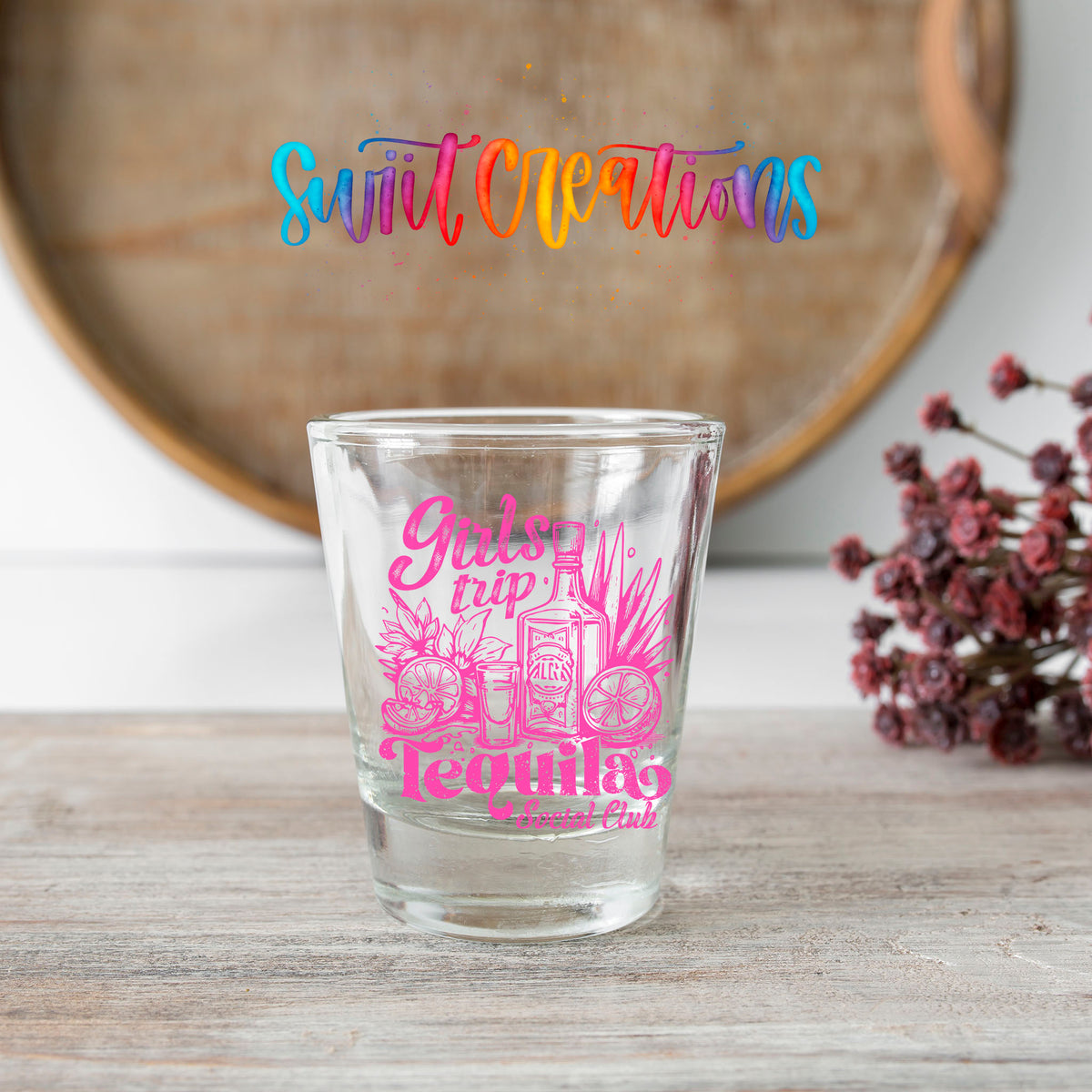 Girls Trip Tequila shot glass transfer on a clear glass beside a wooden barrel and dried flowers