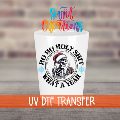 Ho Ho Holy Sh*t What a Year UV DTF transfer on a white shot glass in front of a brick wall