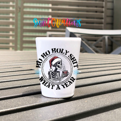 Ho Ho Holy Sh*t What a Year UV DTF transfer on a white shot glass on an outdoor patio table