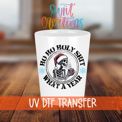 Ho Ho Holy Sh*t What a Year shot glass transfer on a white shot glass on a wooden table