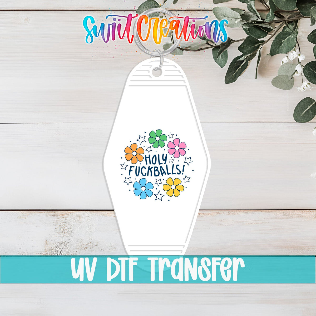 Holy F*ckballs UV DTF transfer on a white motel keychain on a white wood table