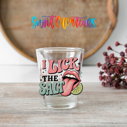 I Lick The Salt shot glass transfer on a clear glass beside a wooden barrel and dried flowers