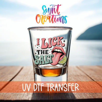 I Lick The Salt shot glass UV DTF transfer on a filled shot glass on a dock by the water