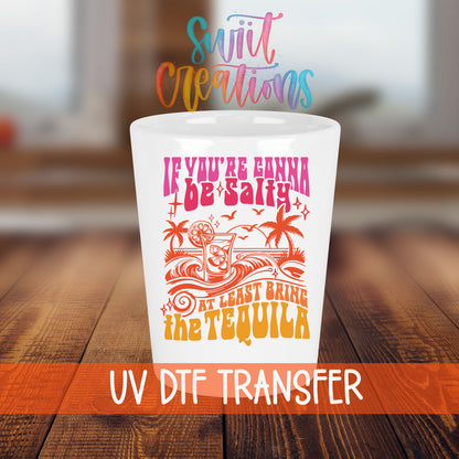 If You're Gonna Be Salty shot glass transfer on a white shot glass on a wooden table