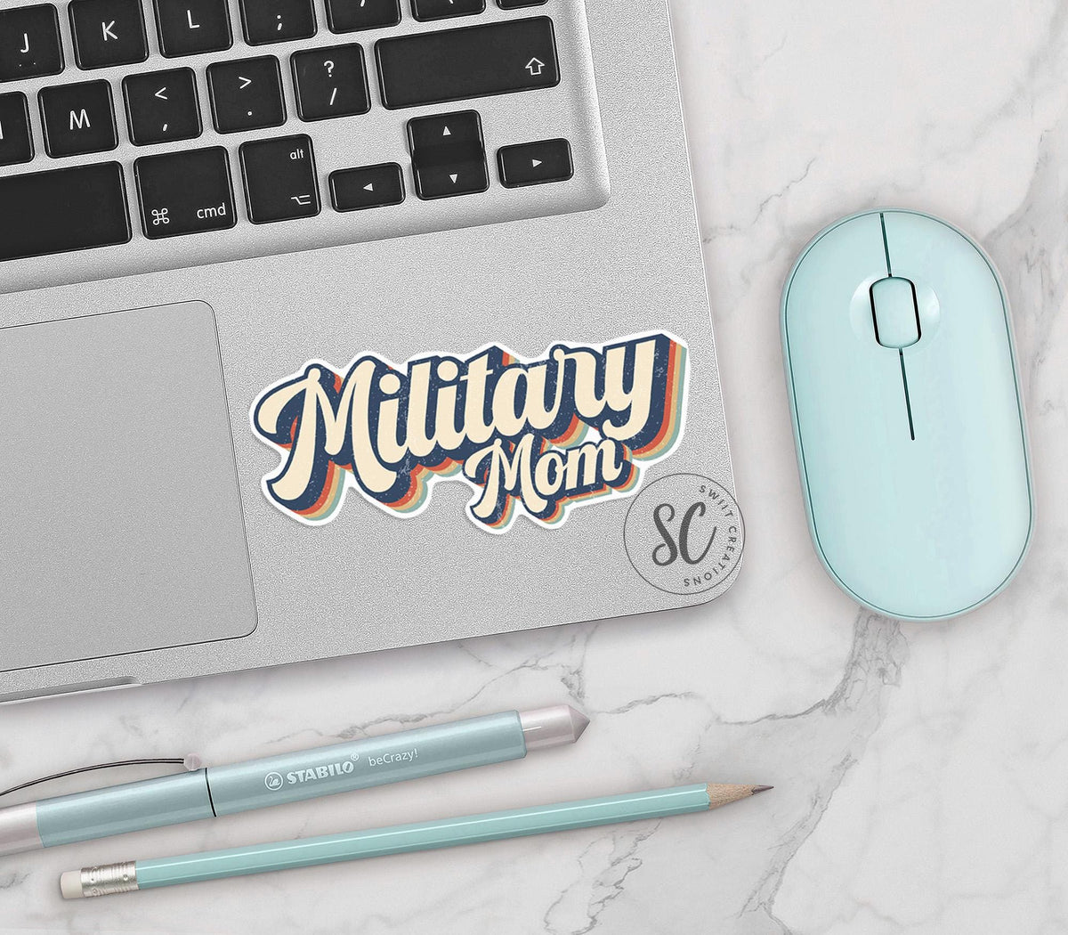 Retro Military Mom vinyl sticker on a silver laptop next to a mint mouse and pens
