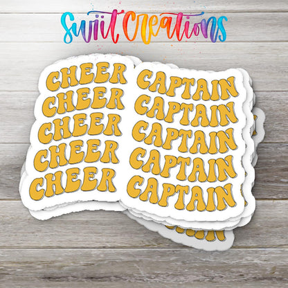 Stack of Gold Retro Cheer Captain glossy stickers on a gray wood table