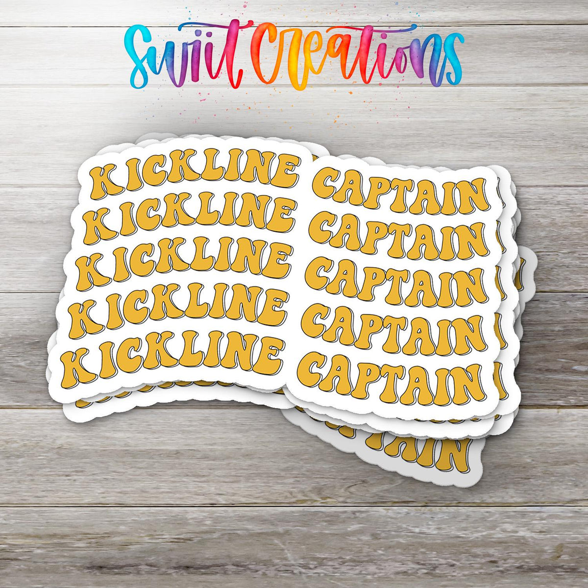 Stack of Gold Retro Kickline Captain glossy stickers on a gray wood table