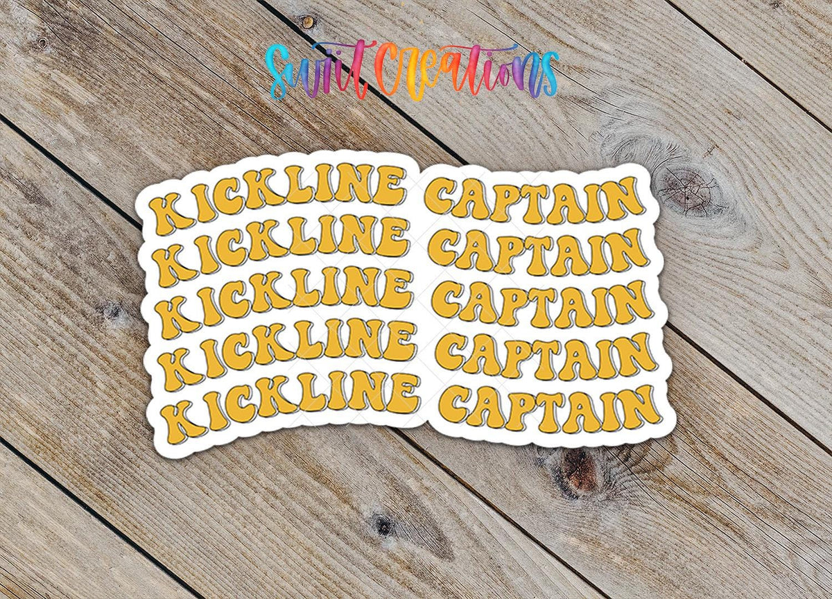Close-up of the Gold Retro Kickline Captain sticker on rustic wood
