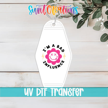 I'm a Bad Influence UV DTF transfer on a white motel keychain on a white wood table