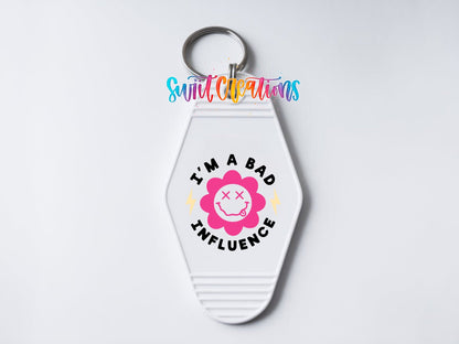 Close-up of the I'm a Bad Influence UV DTF transfer on a white motel keychain