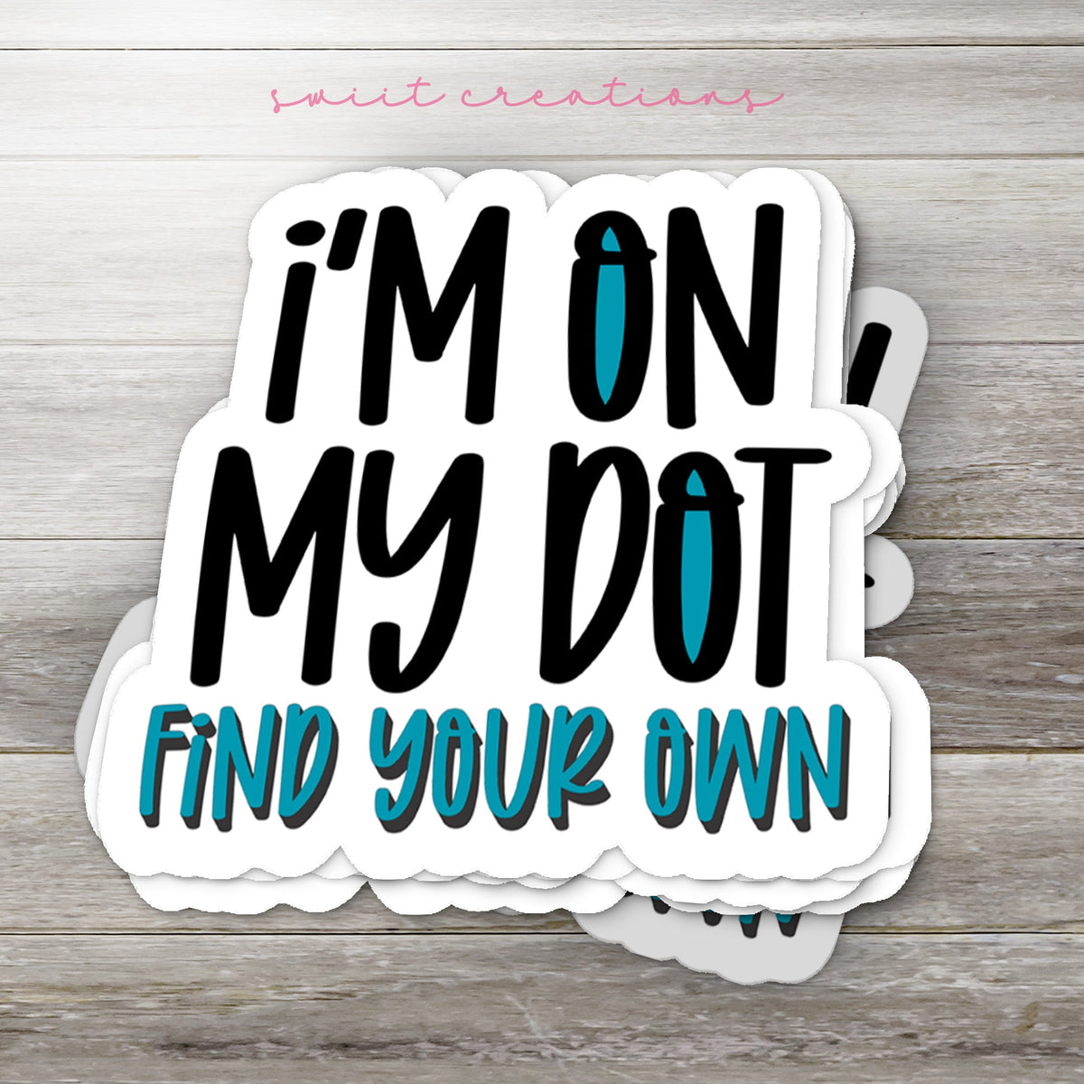 Stack of I'm On My Dot glossy stickers on a gray wood table