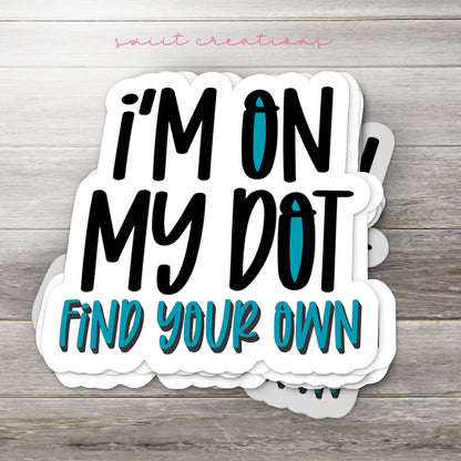 Stack of I'm On My Dot glossy stickers on a gray wood table