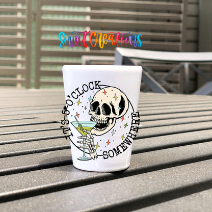 It's 5 O'Clock Somewhere UV DTF transfer on a white shot glass on an outdoor patio table