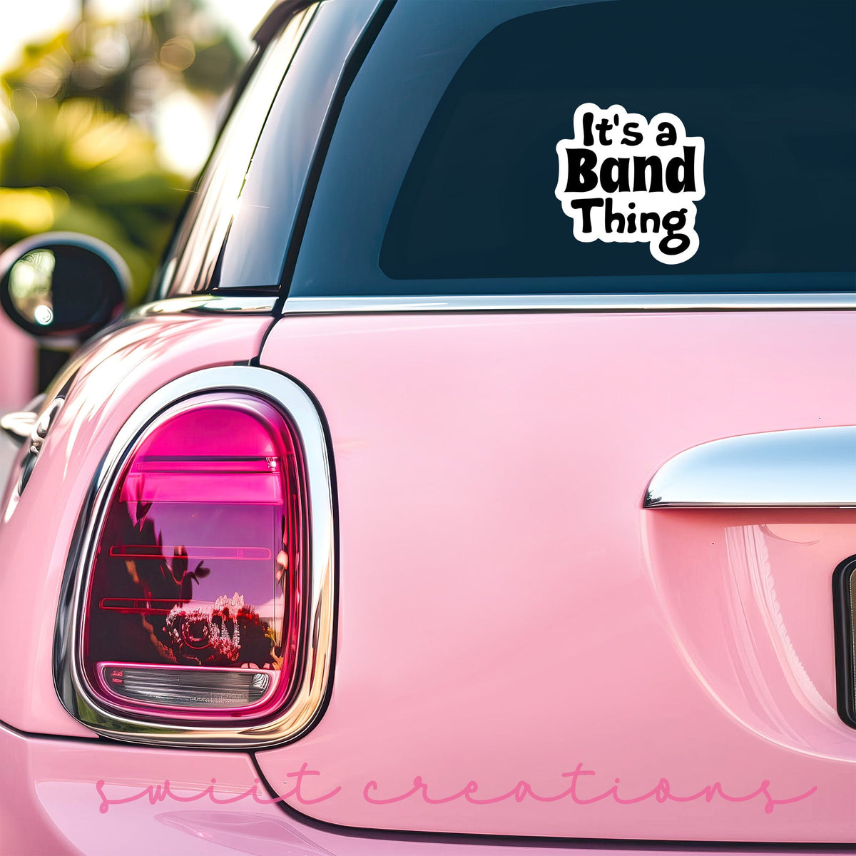Black It's a Band Thing sticker on the back window of a pink car