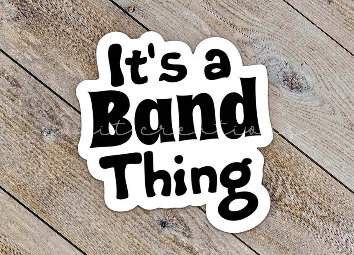 Close-up of the Black It's a Band Thing sticker on rustic wood