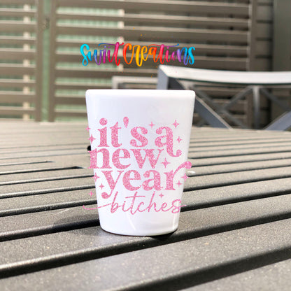 It's A New Year B*tches UV DTF transfer on a white shot glass on an outdoor patio table
