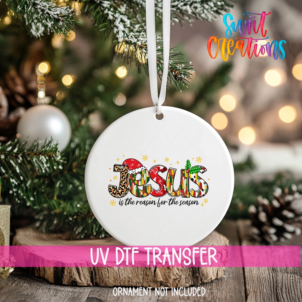 Jesus Is the Reason for the Season ornament UV DTF transfer on an ornament resting on a wood slice beside a Christmas tree