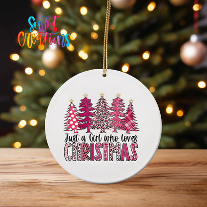 Just a Girl Who Loves Christmas ornament UV DTF transfer on an ornament on a wooden table with tree lights behind it