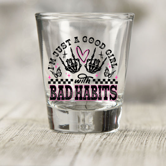 Just a Good Girl with Bad Habits shot glass UV DTF transfer with skeleton hands, heart, butterflies, and checkerboard on a clear shot glass