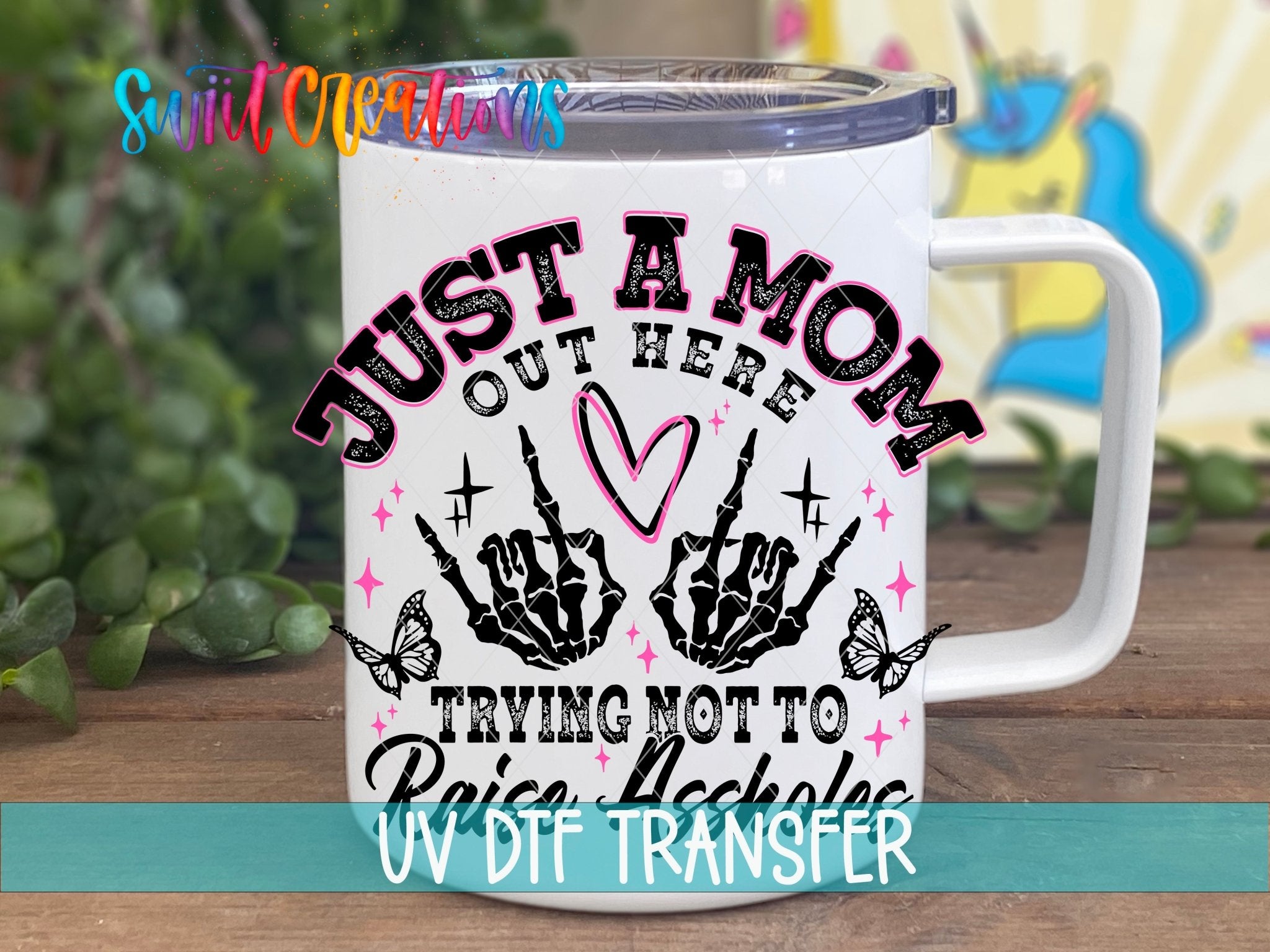 Just a Mom Trying Not To Raise Assholes UV DTF transfer displayed on a white coffee mug from Swiit Creations