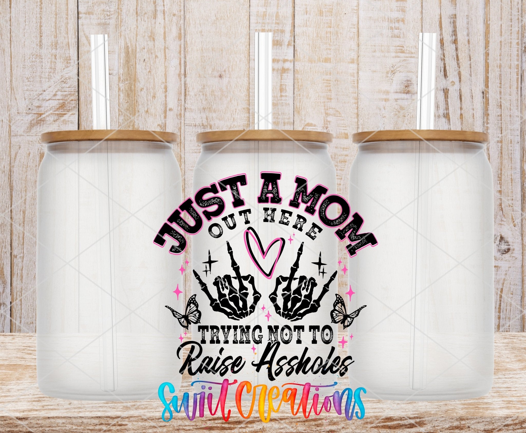 Just a Mom Trying Not To Raise Assholes UV DTF transfer applied to a clear glass can set from Swiit Creations