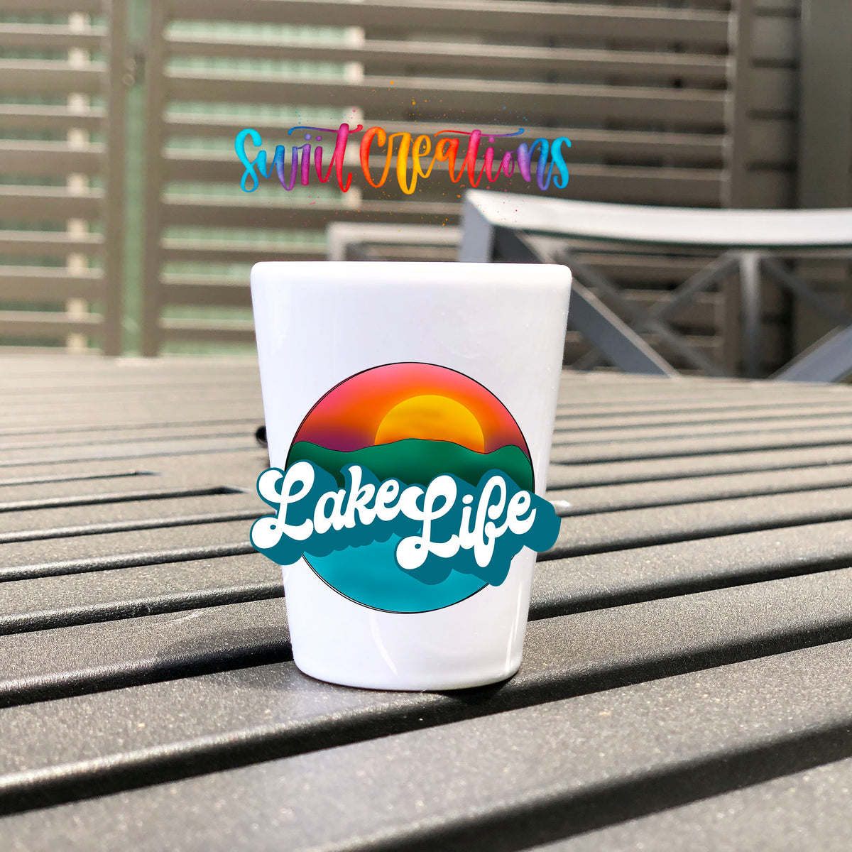 Lake Life UV DTF transfer on a white shot glass on an outdoor patio table